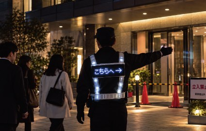 LEDベストを着用して夜間に歩行者を誘導する警備員